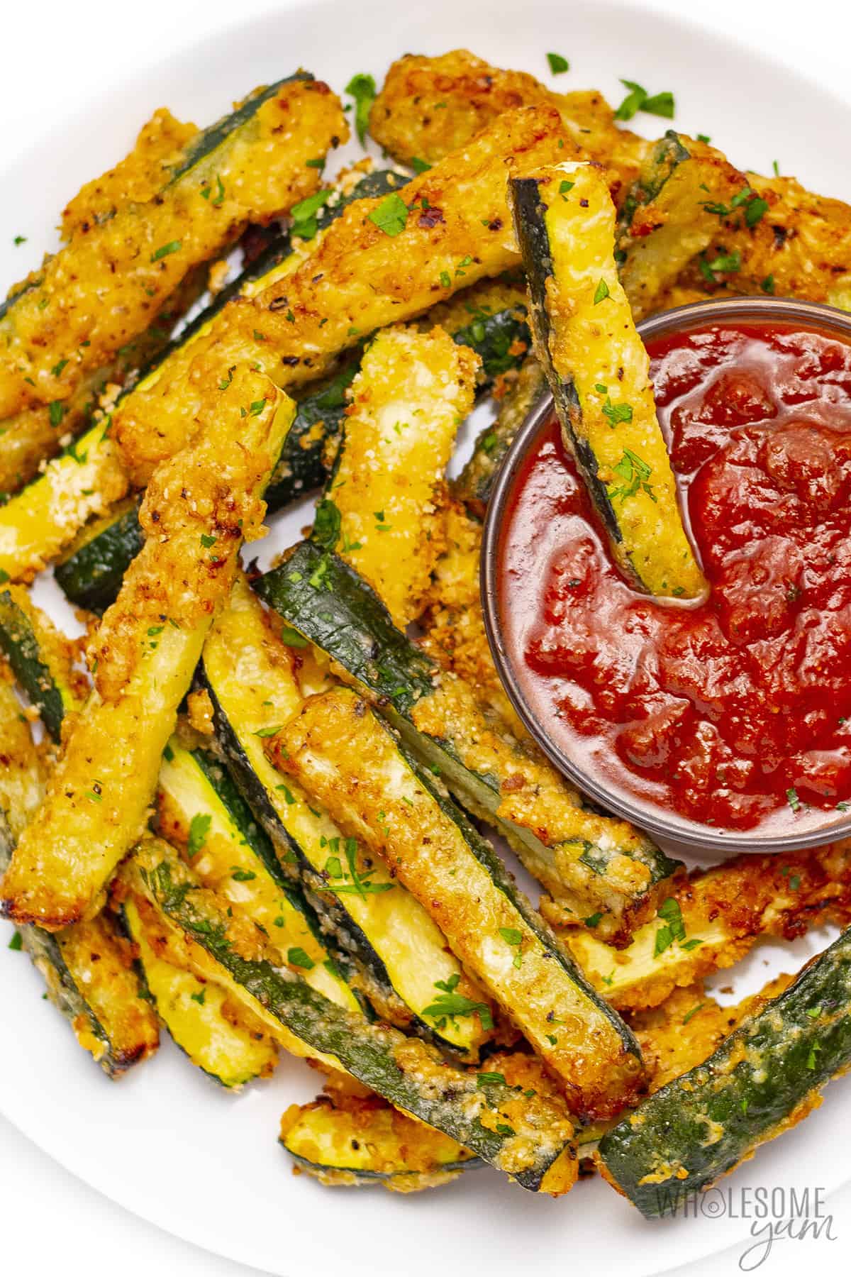 Zucchini fries with one fry dipped in marinara.