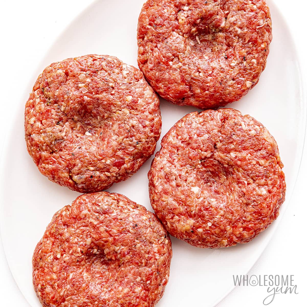 Hamburger shaped into patties with a thumb print in the center.
