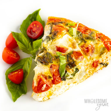Slice of crustless quiche with tomatoes and basil on a plate