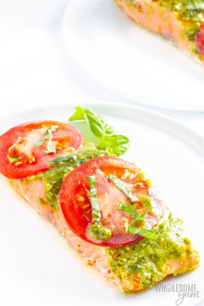 Basil pesto salmon fillet on a plate with tomatoes and basil