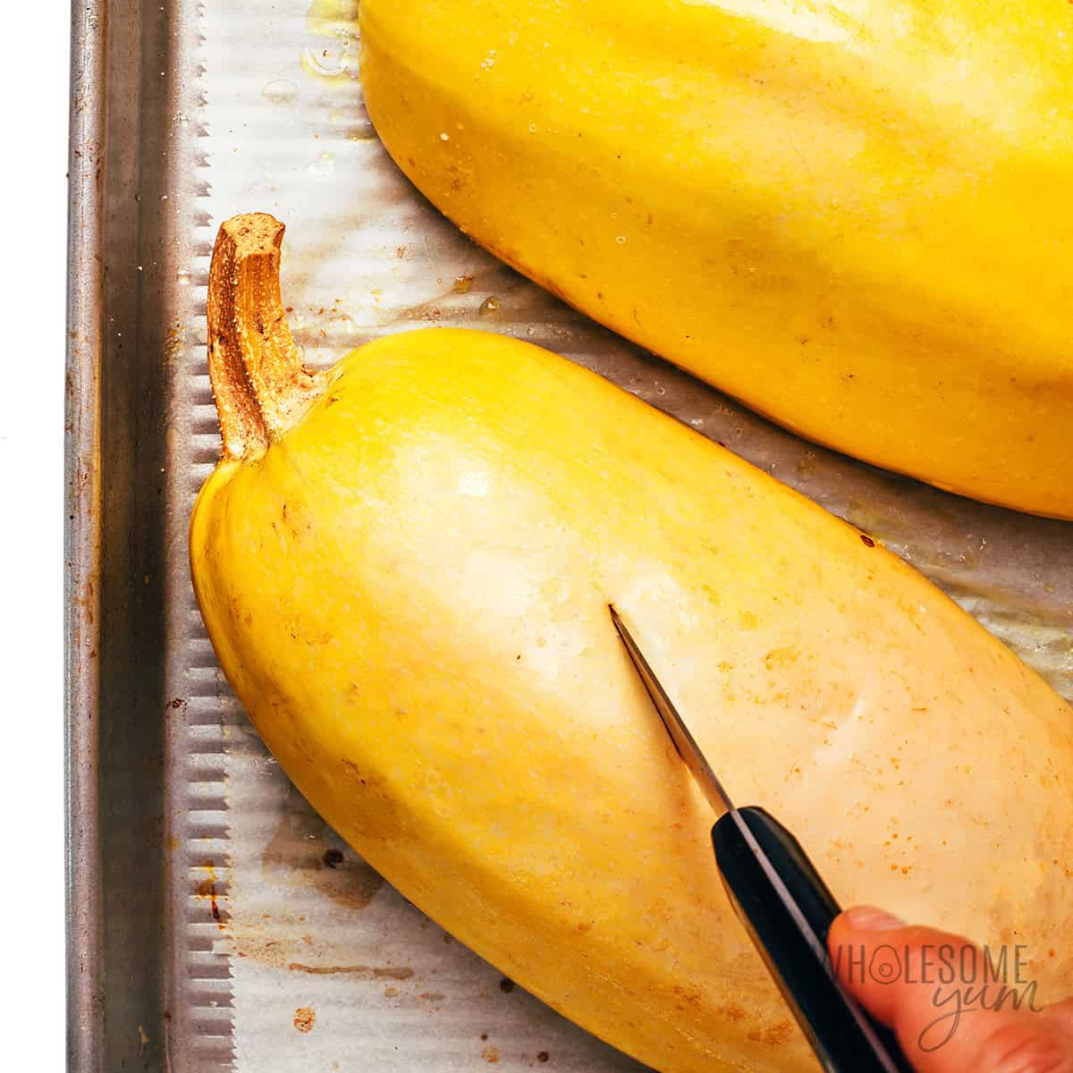 Roasted spaghetti squash with a knife showing doneness.