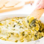 keto spinach artichoke dip with a cracker dipping into it