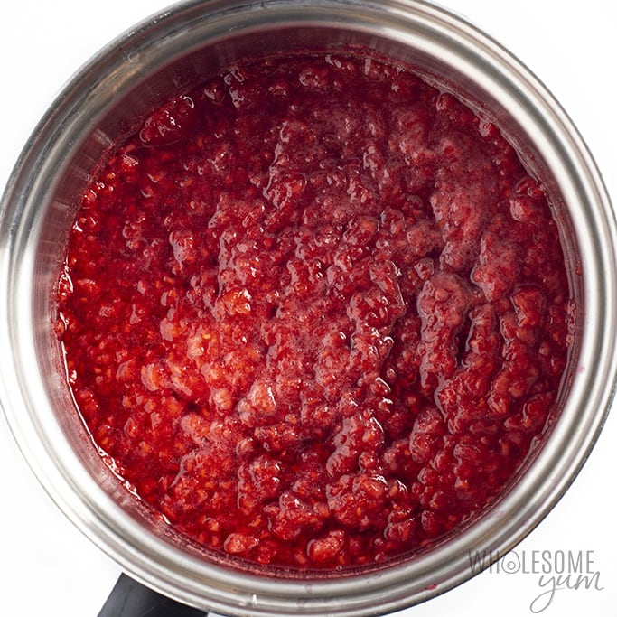 Overhead view of mashed raspberries in small saucepan