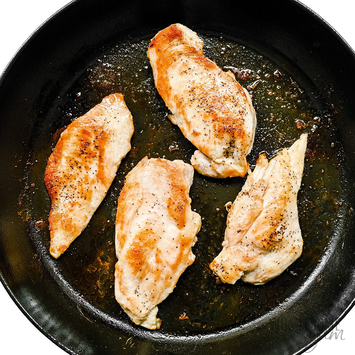 Chicken breasts searing in cast iron skillet.