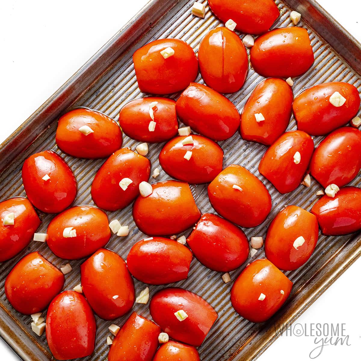 Tomatoes and garlic on a baking sheet.