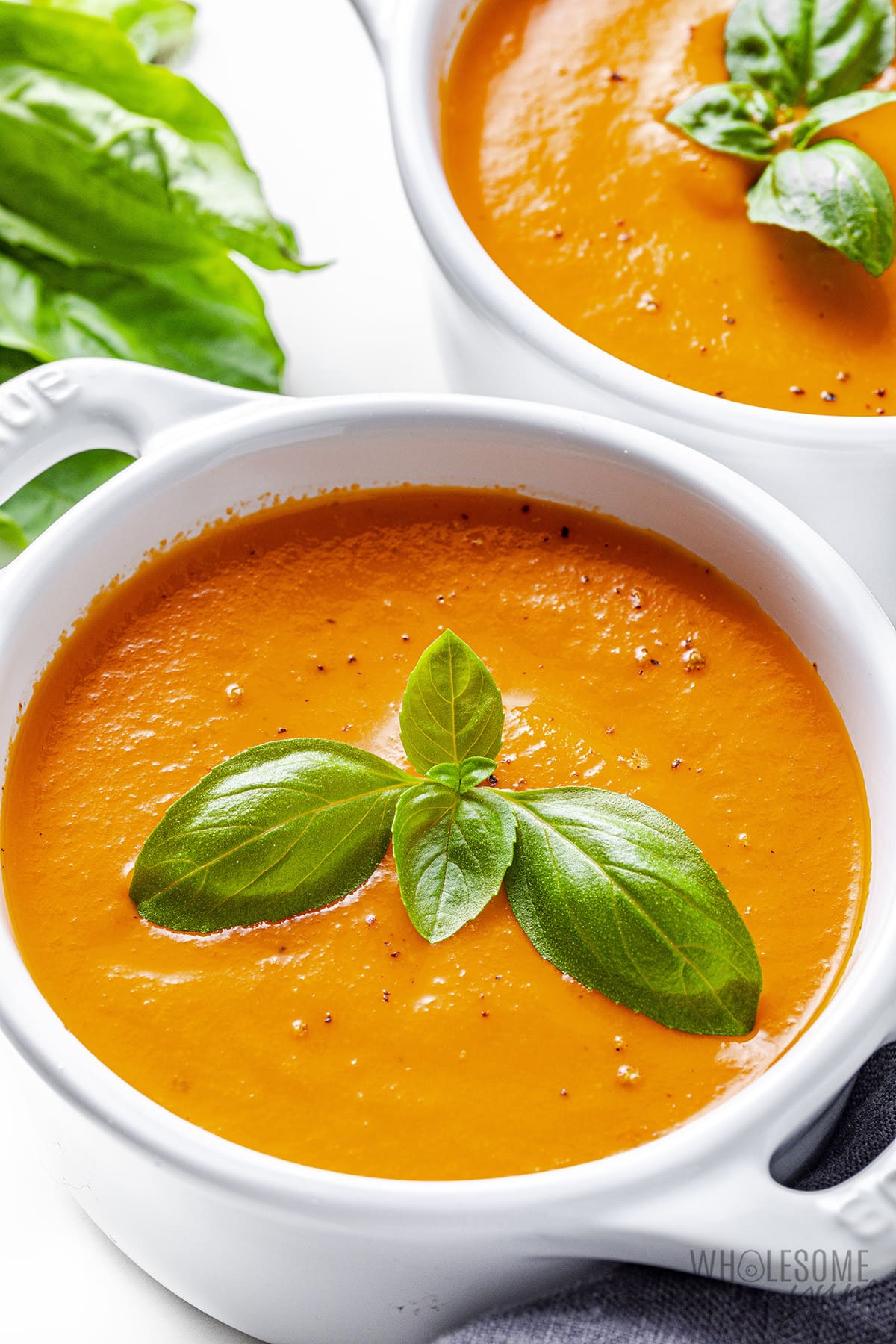 Roasted tomato soup in bowls garnished with fresh basil.