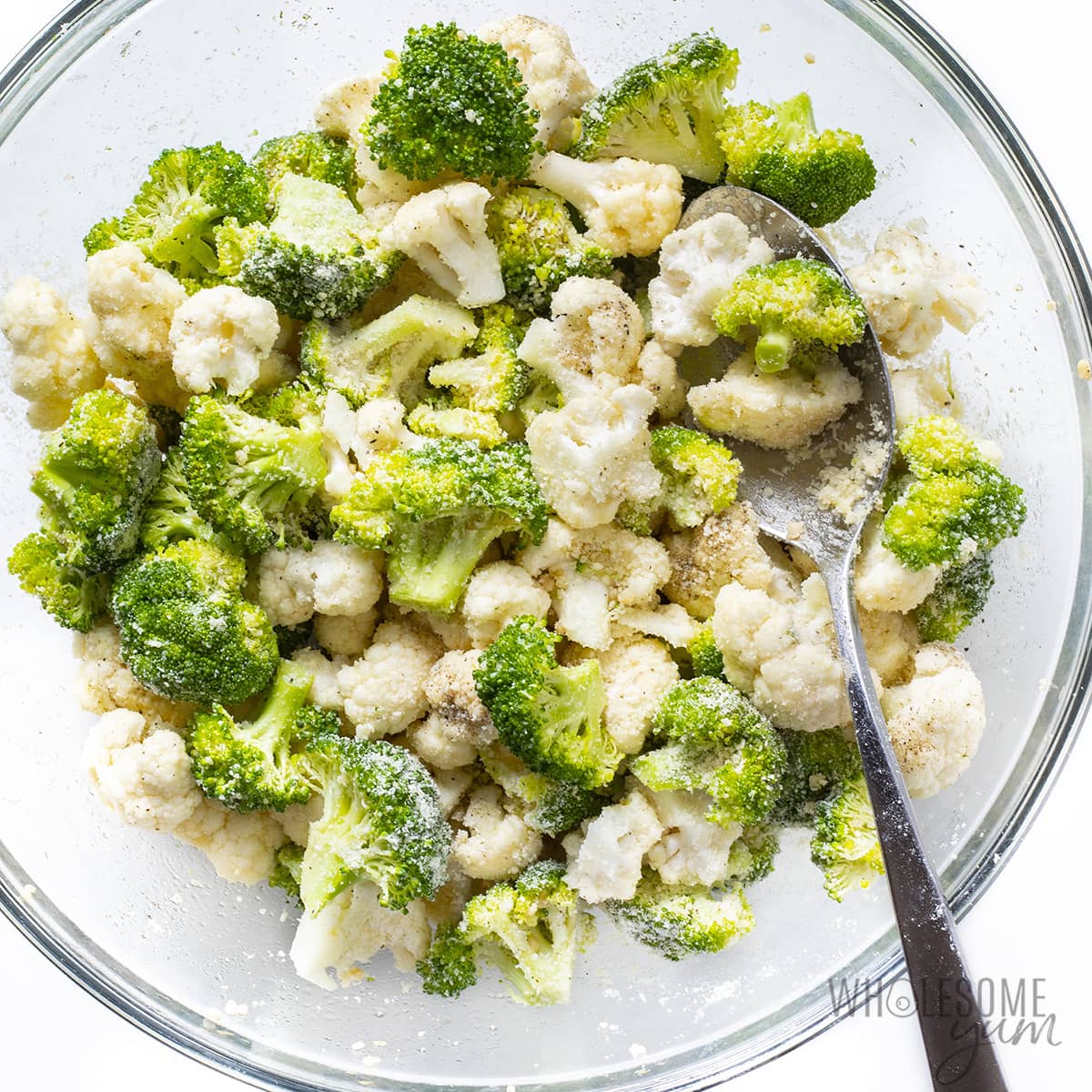 Broccoli and cauliflower in a bowl tossed with olive oil, parmesan, garlic, salt, and pepper.
