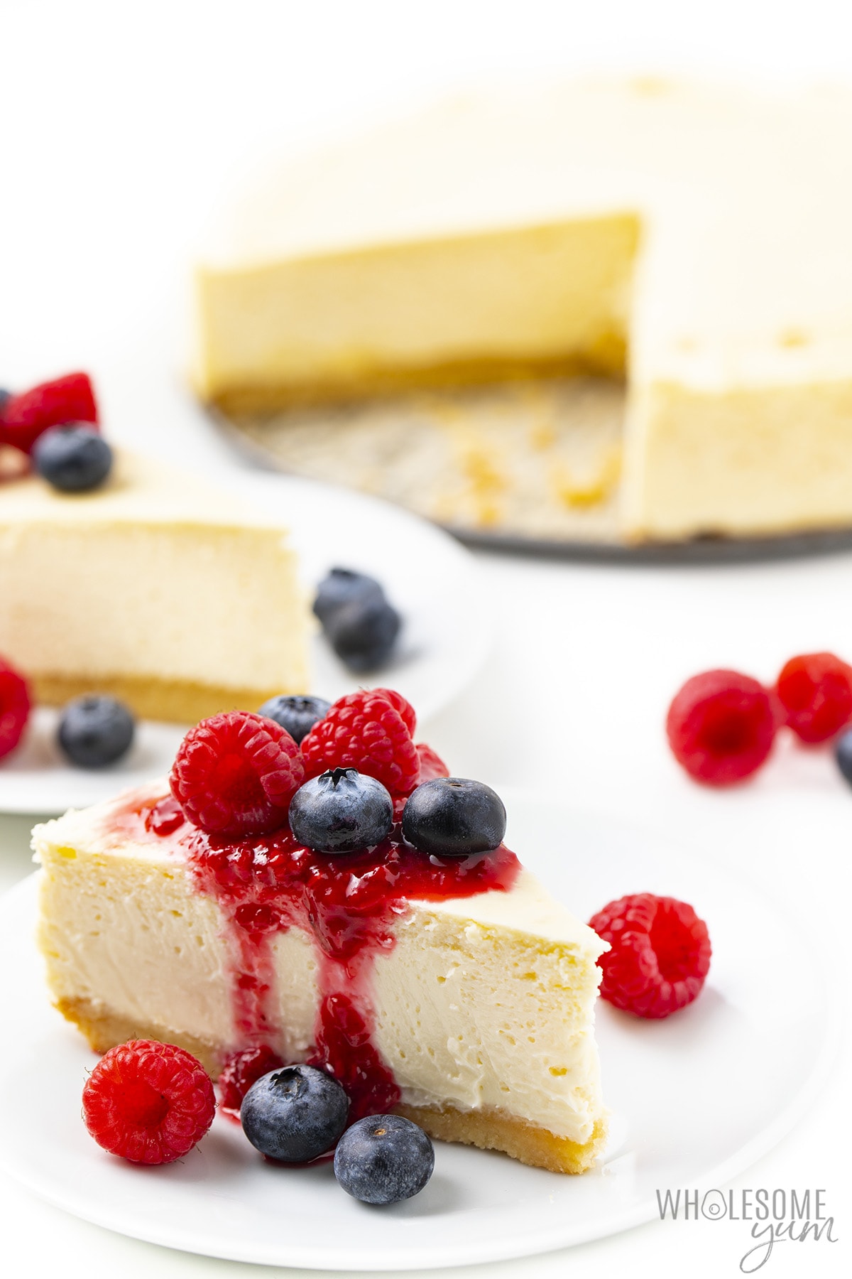 Slice of sugar-free cheesecake with whole cake in the background.