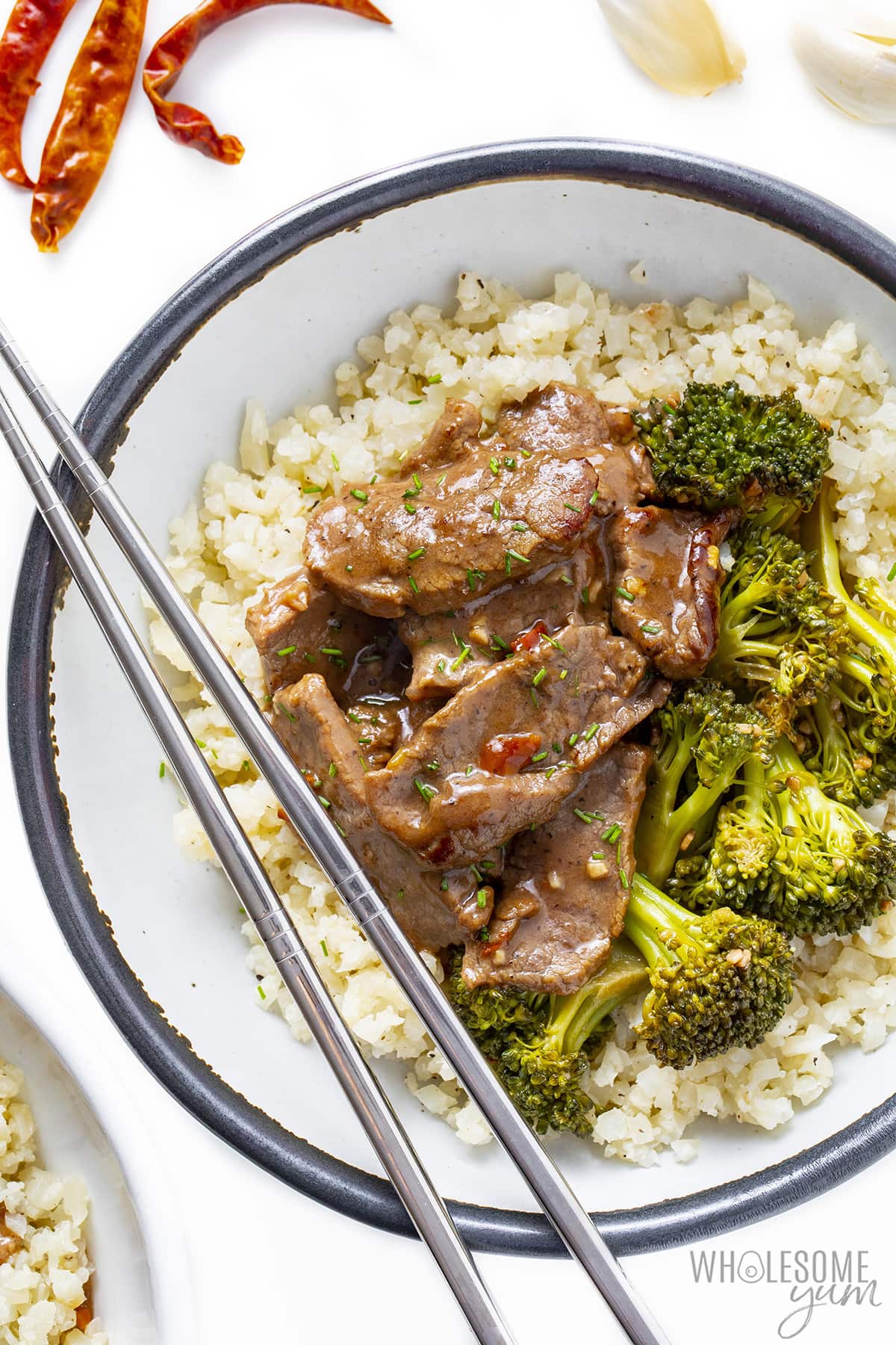 Hunan beef over a bed of cauliflower rice with broccoli.