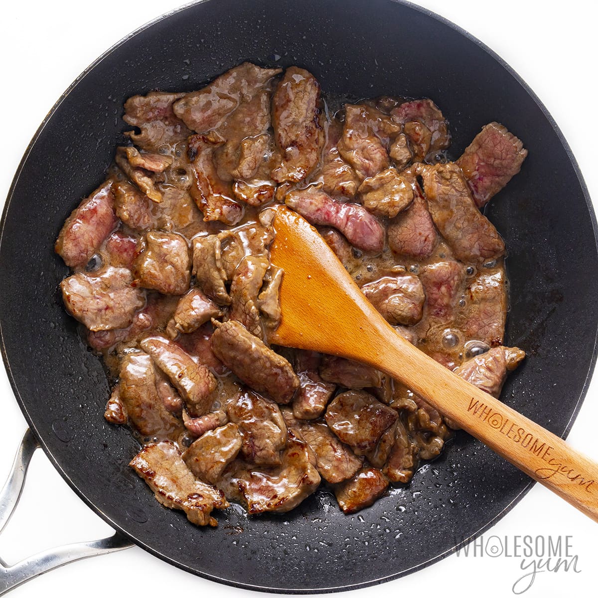 Beef cooking with marinade in a pan.