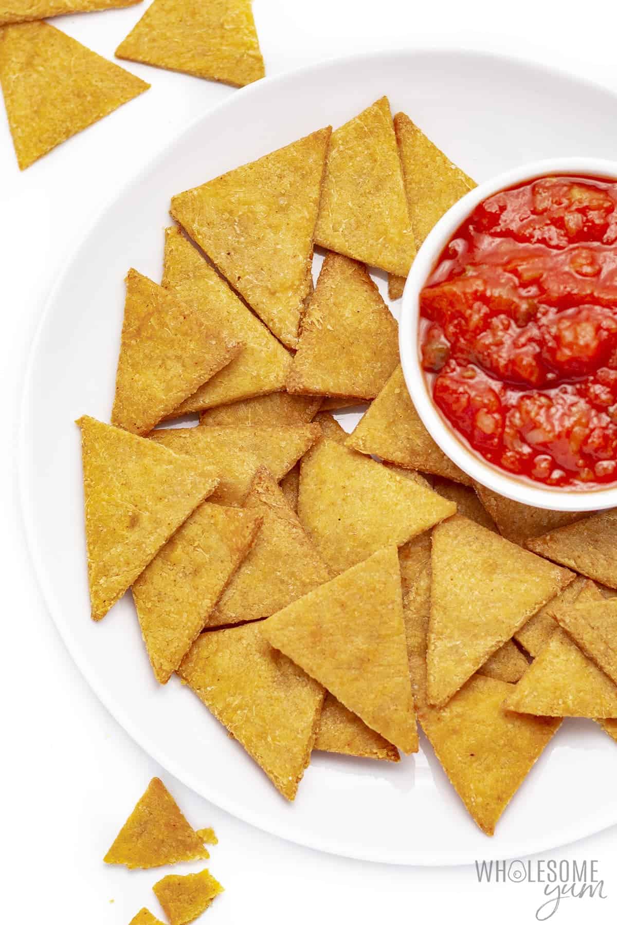 Low carb chips on a plate next to bowl of salsa.
