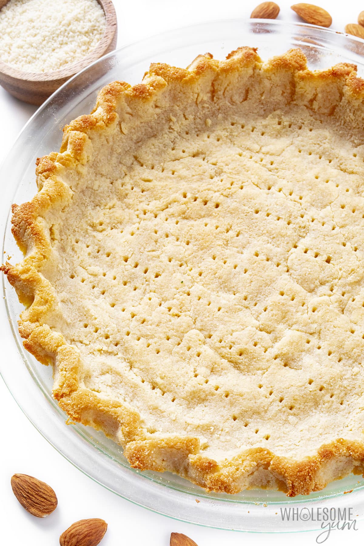Keto pie crust next to cup of almond flour.