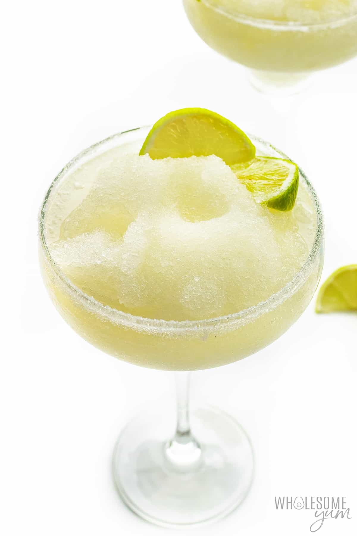 Keto margarita in a glass with lime wedges.