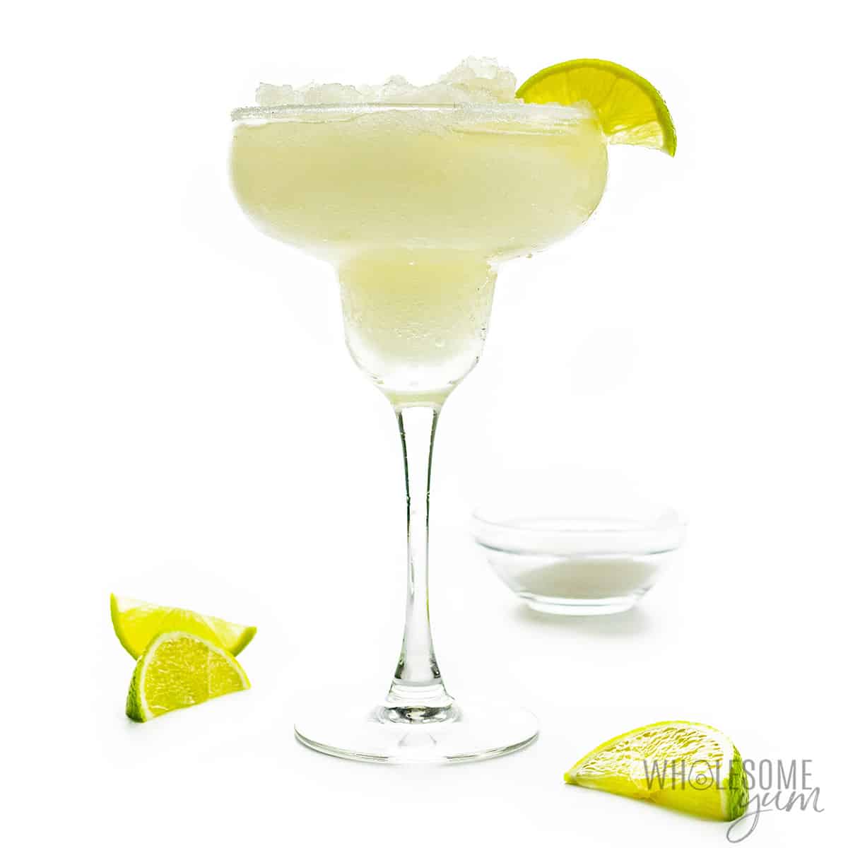 Skinny margarita in glass with lime wedges. 