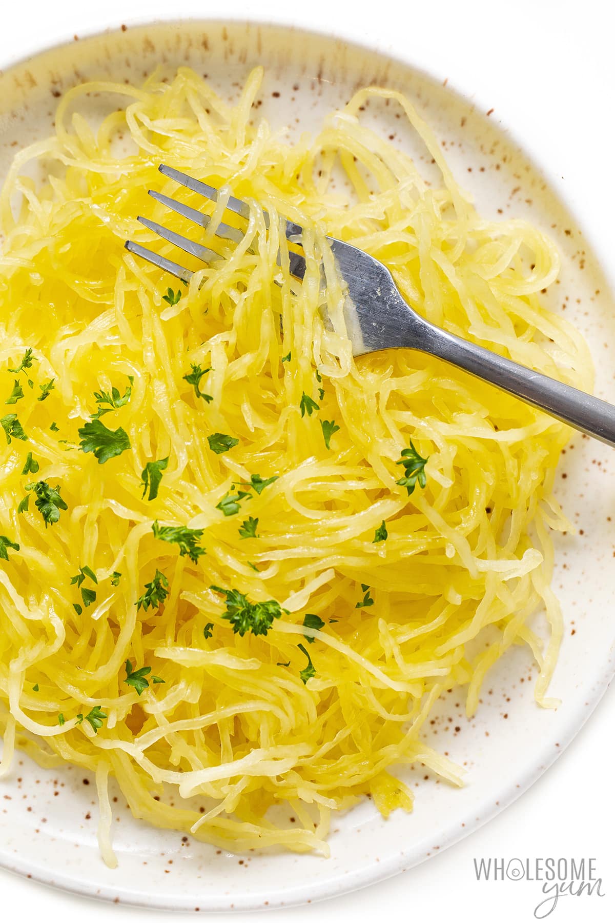 Baked spaghetti squash strands on a plate with a fork.