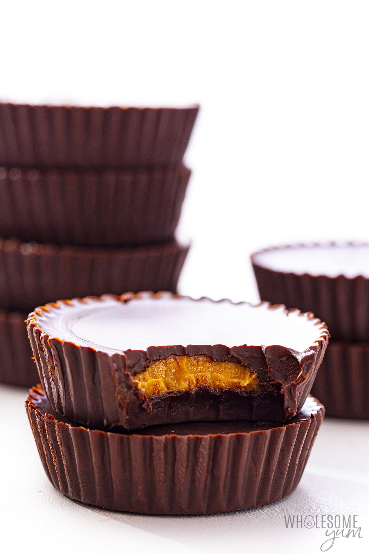 Keto peanut butter cup stacks on a white background, with a bite taken out of one of them.