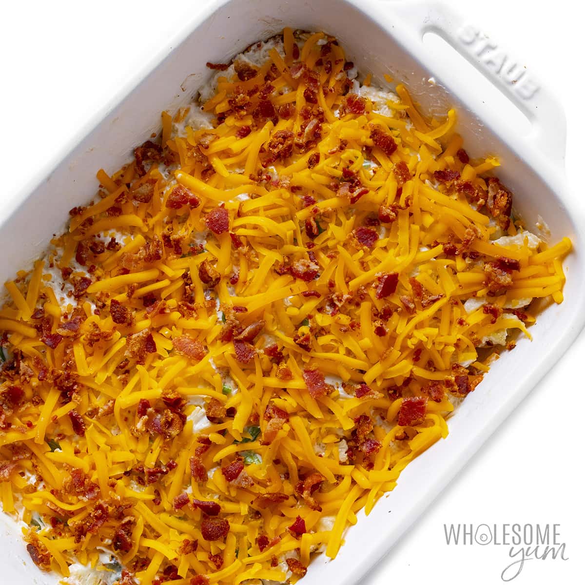 Loaded cauliflower casserole topped with cheese and bacon in a baking dish.
