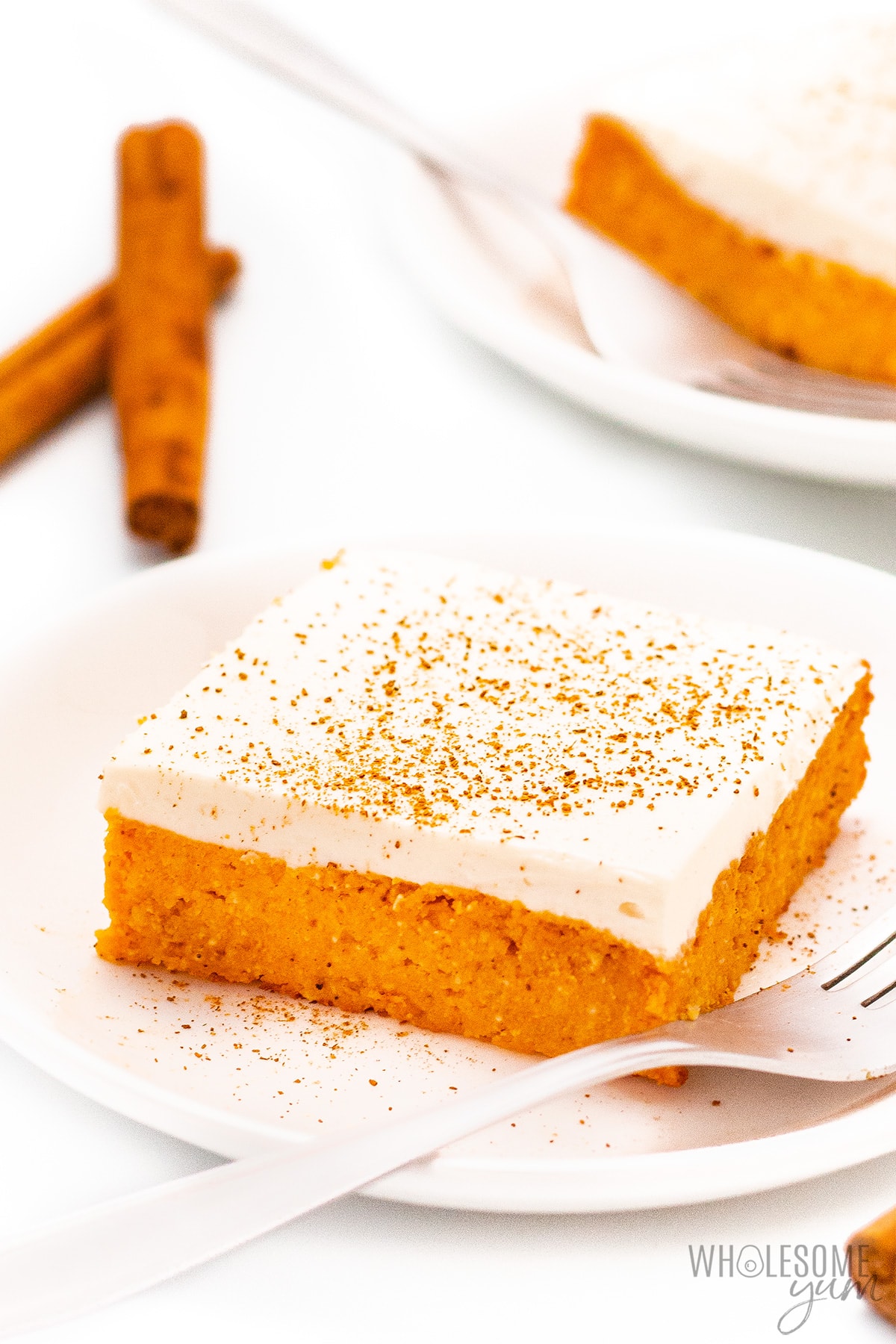 Pumpkin bars with cream cheese frosting on plates.