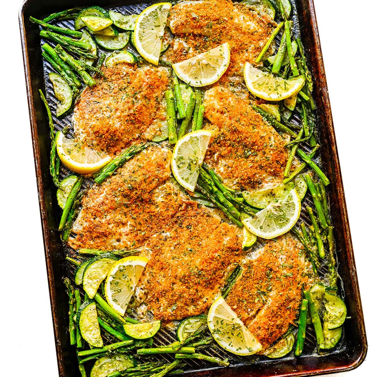 Baked parmesan crusted tilapia on a sheet pan with veggies. 