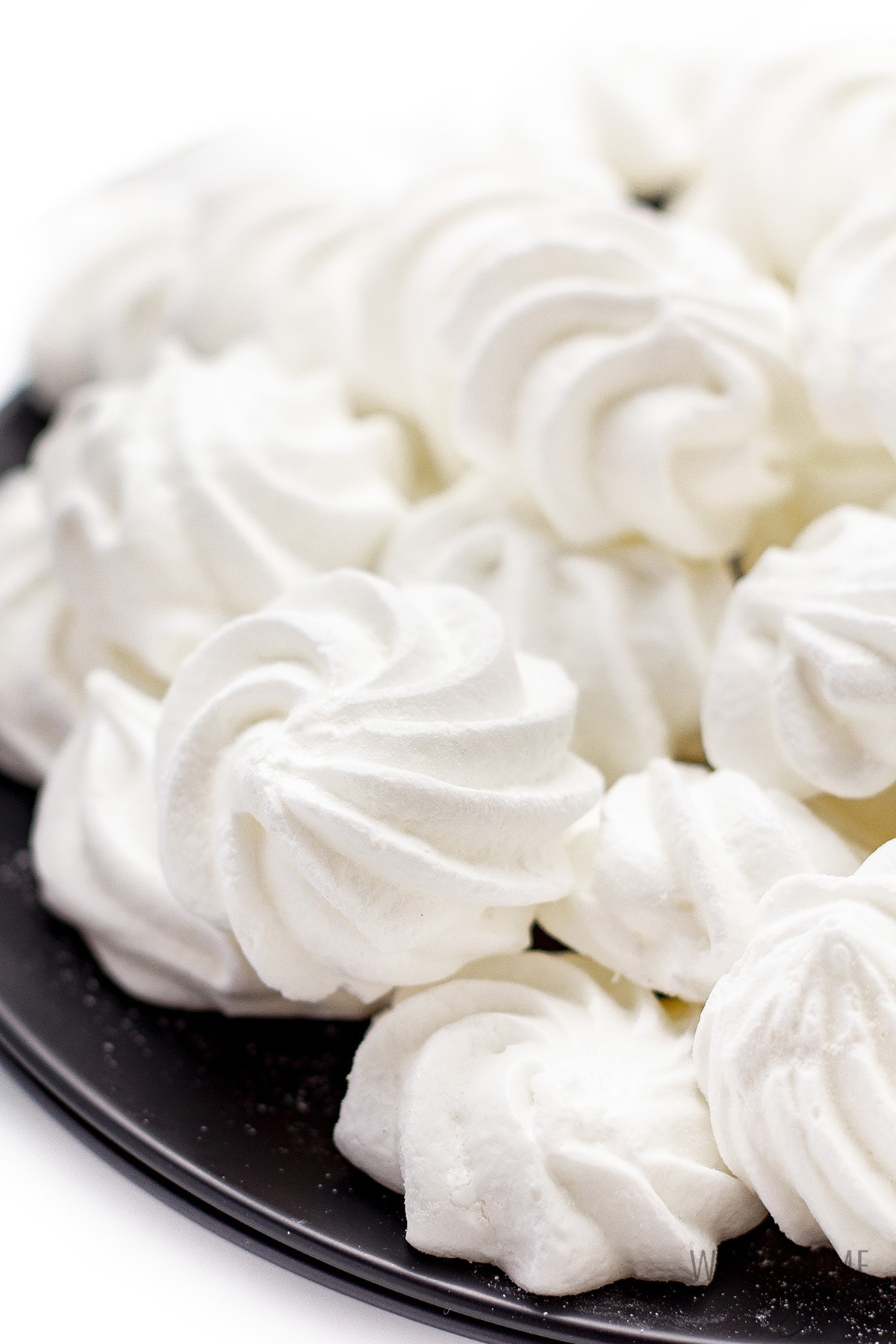 Keto meringue cookies stacked on a plate.