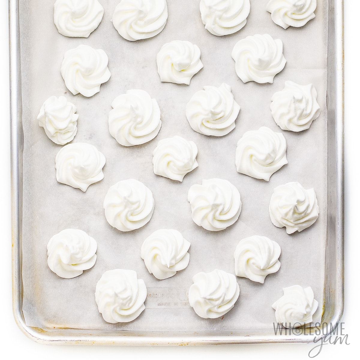 Meringues lined up on a baking sheet.