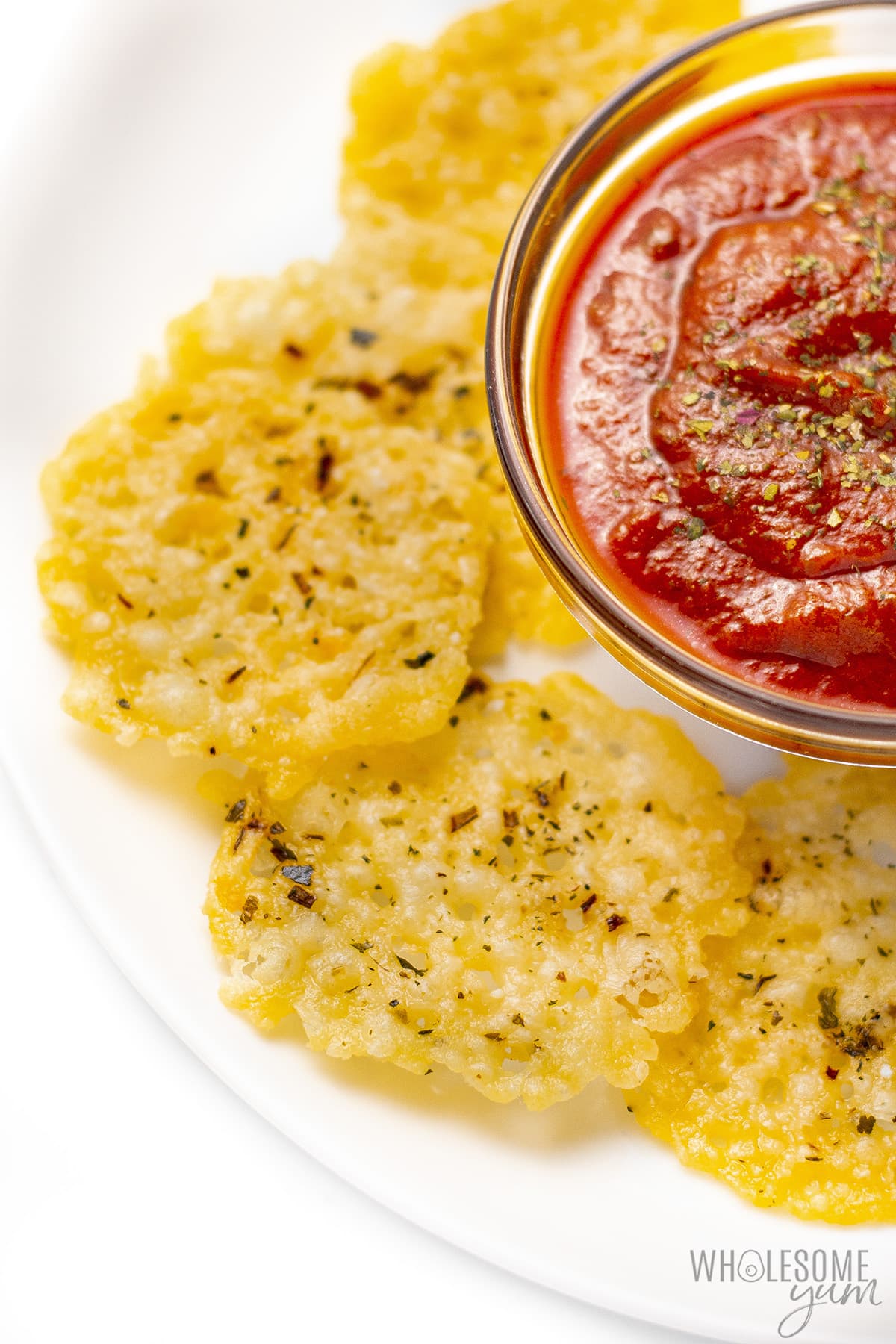 Parmesan crisps on a plate with marinara sauce.