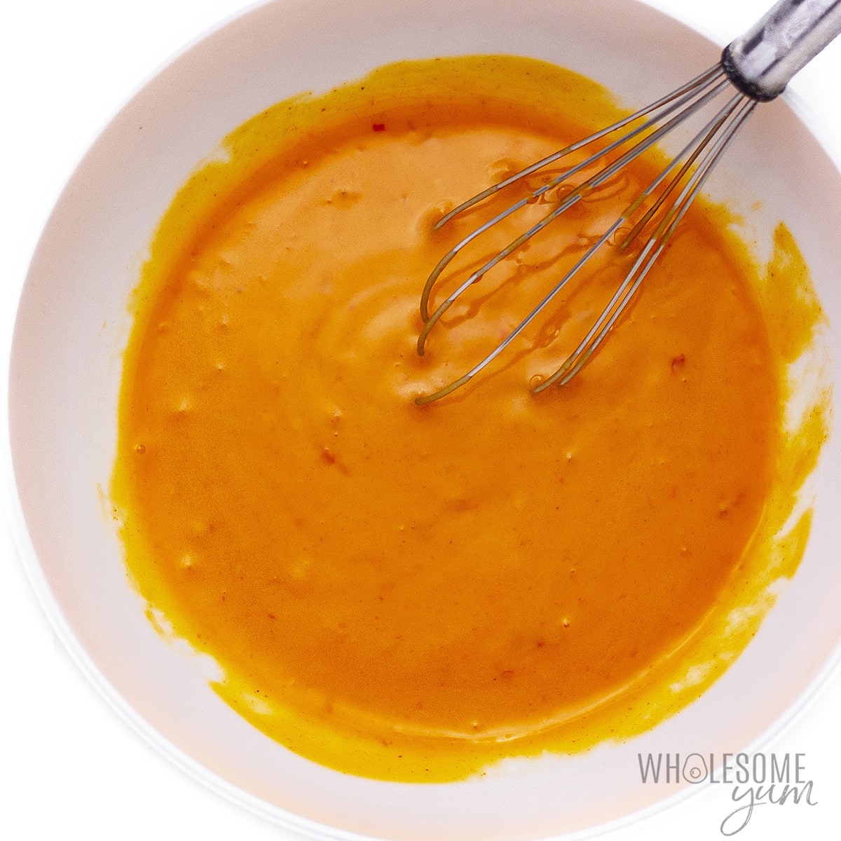 Buffalo sauce and butter whisked in a bowl.