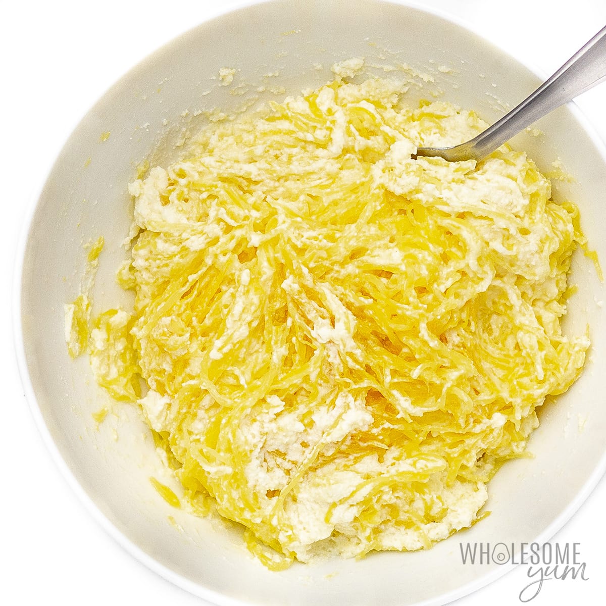 Spaghetti squash strands stirred together with cheese mixture.