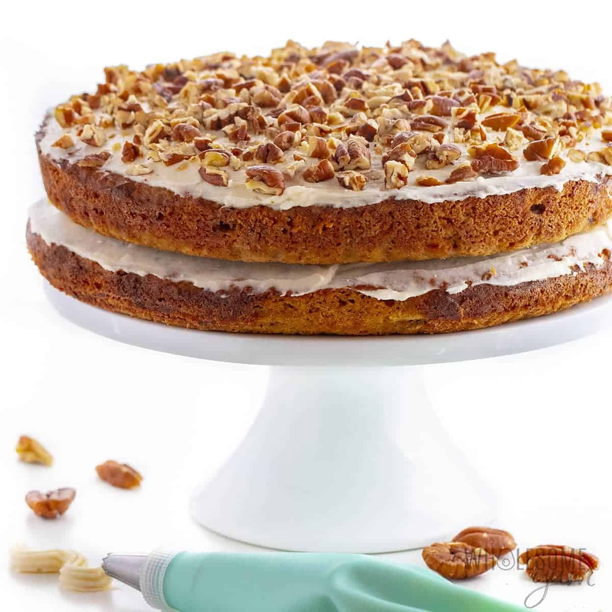 Keto friendly carrot cake on a cake stand with piping set.