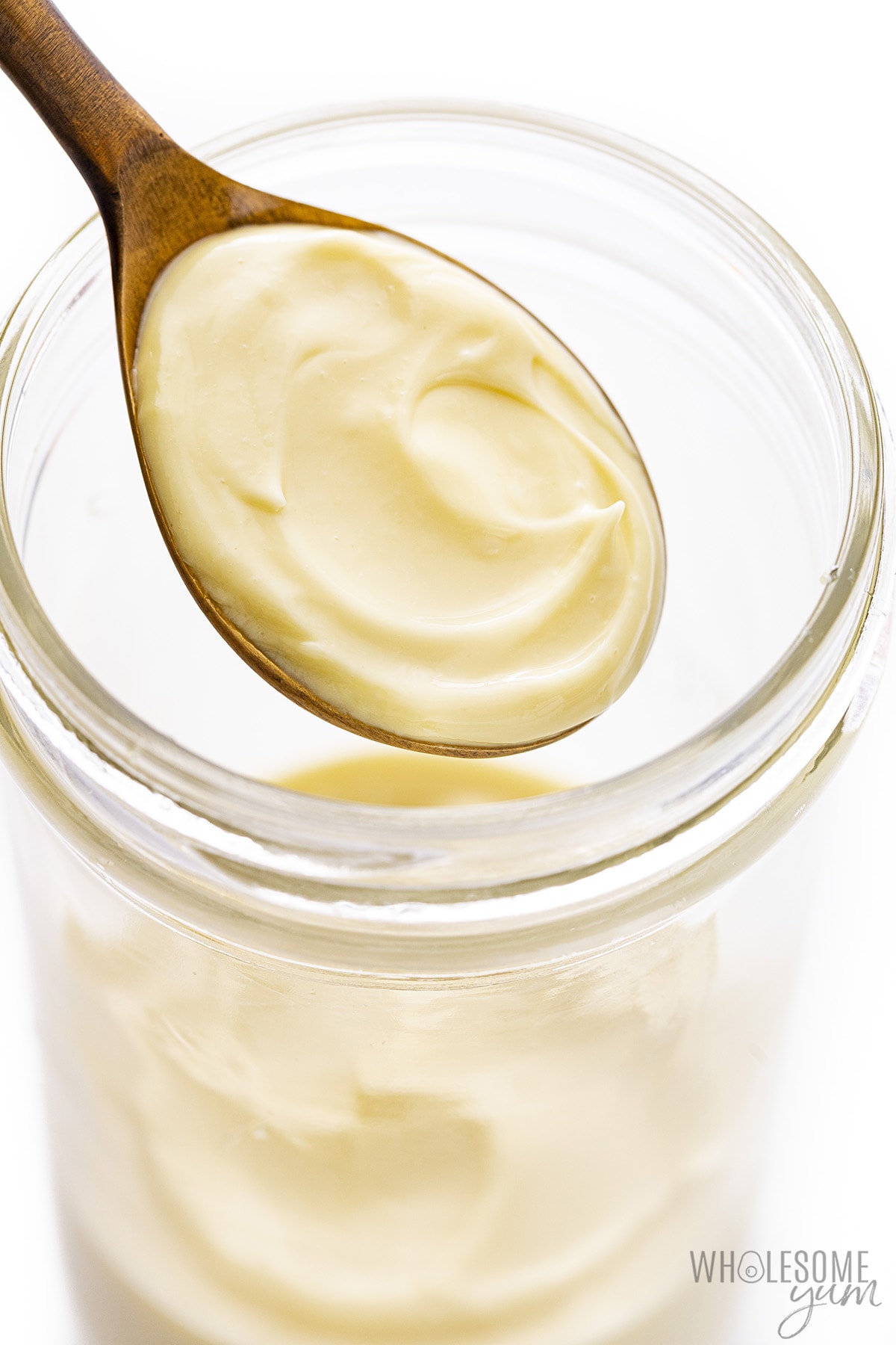 Homemade mayo in a jar with a spoon.