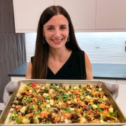 Me holding a large sheet pan of cauliflower nachos.