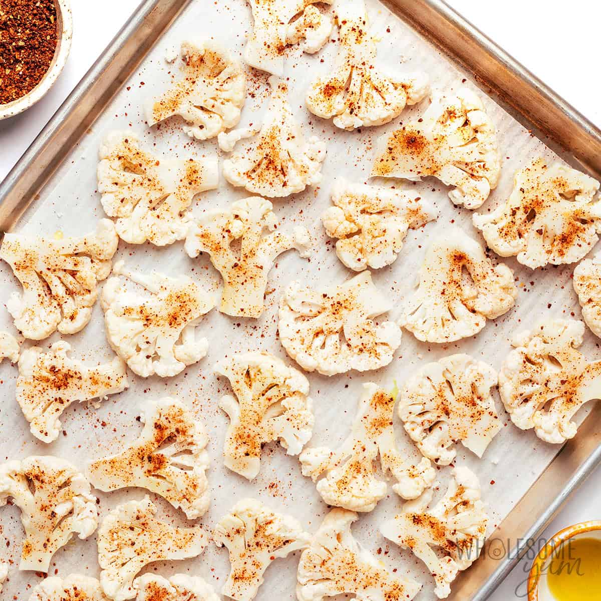 Seasoned cauliflower chips on a baking sheet.