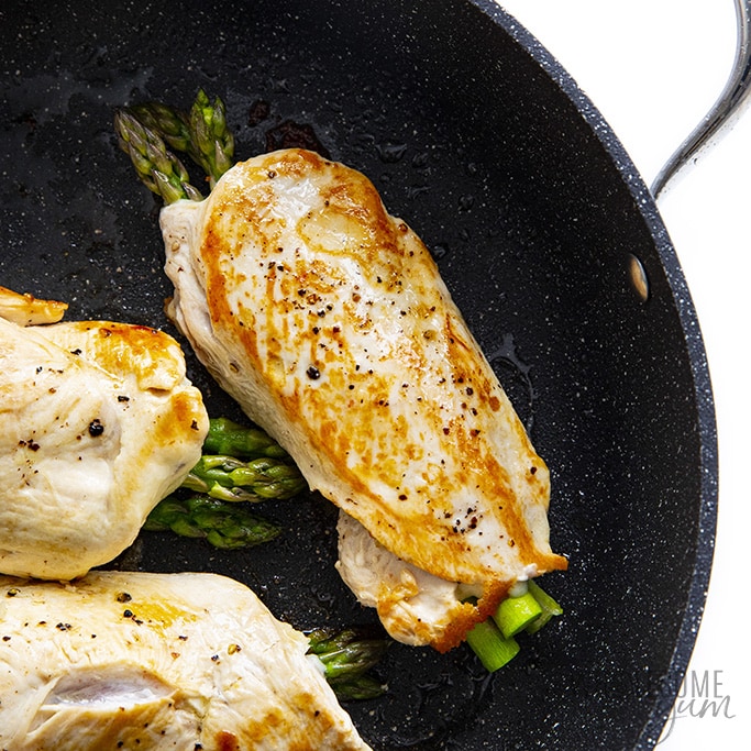 Asparagus stuffed chicken breasts browning in a pan