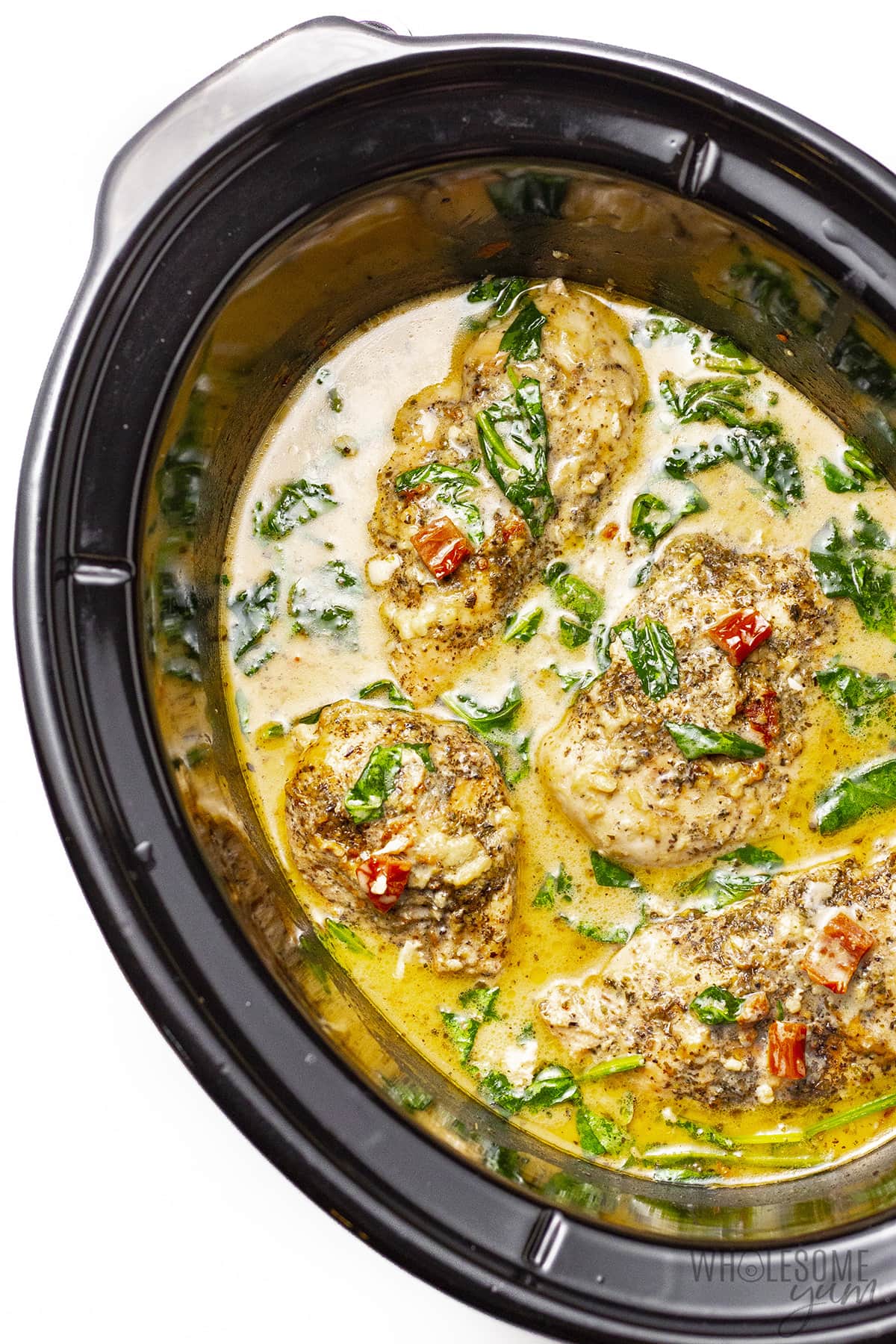 Overhead view of creamy Tuscan chicken in Crock Pot.