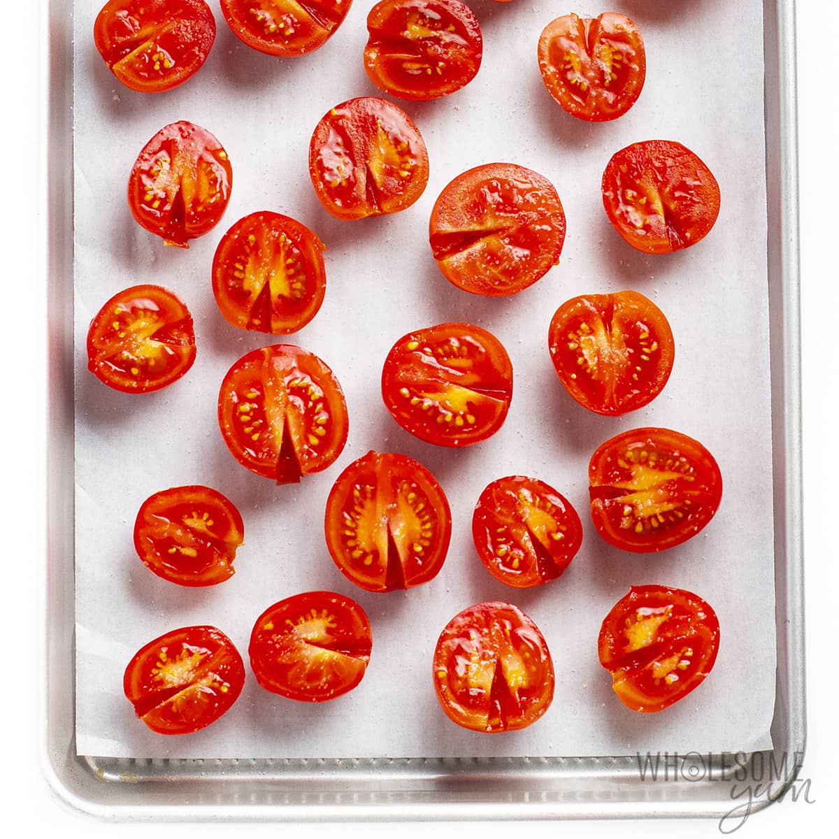 Raw tomatoes on a baking sheet.