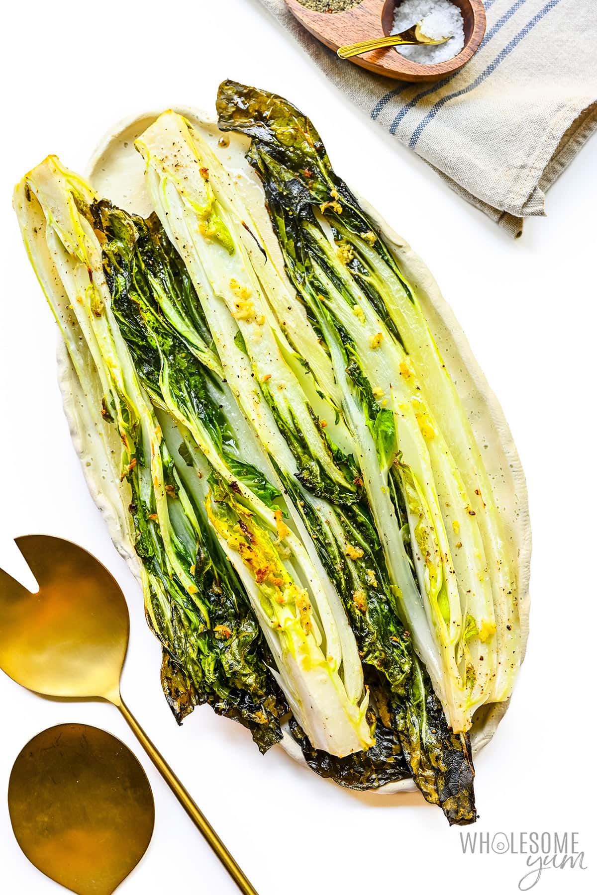 Bok choy recipe on a platter next to serving spoons.