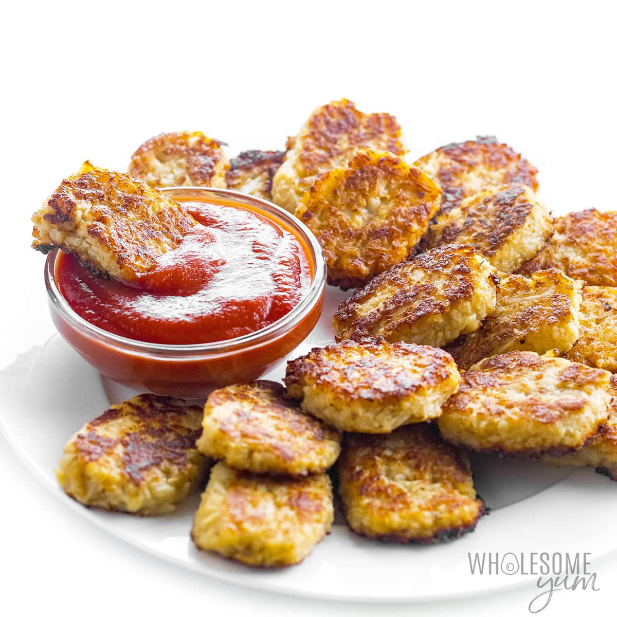Tater tot in bowl of ketchup with others spread around.