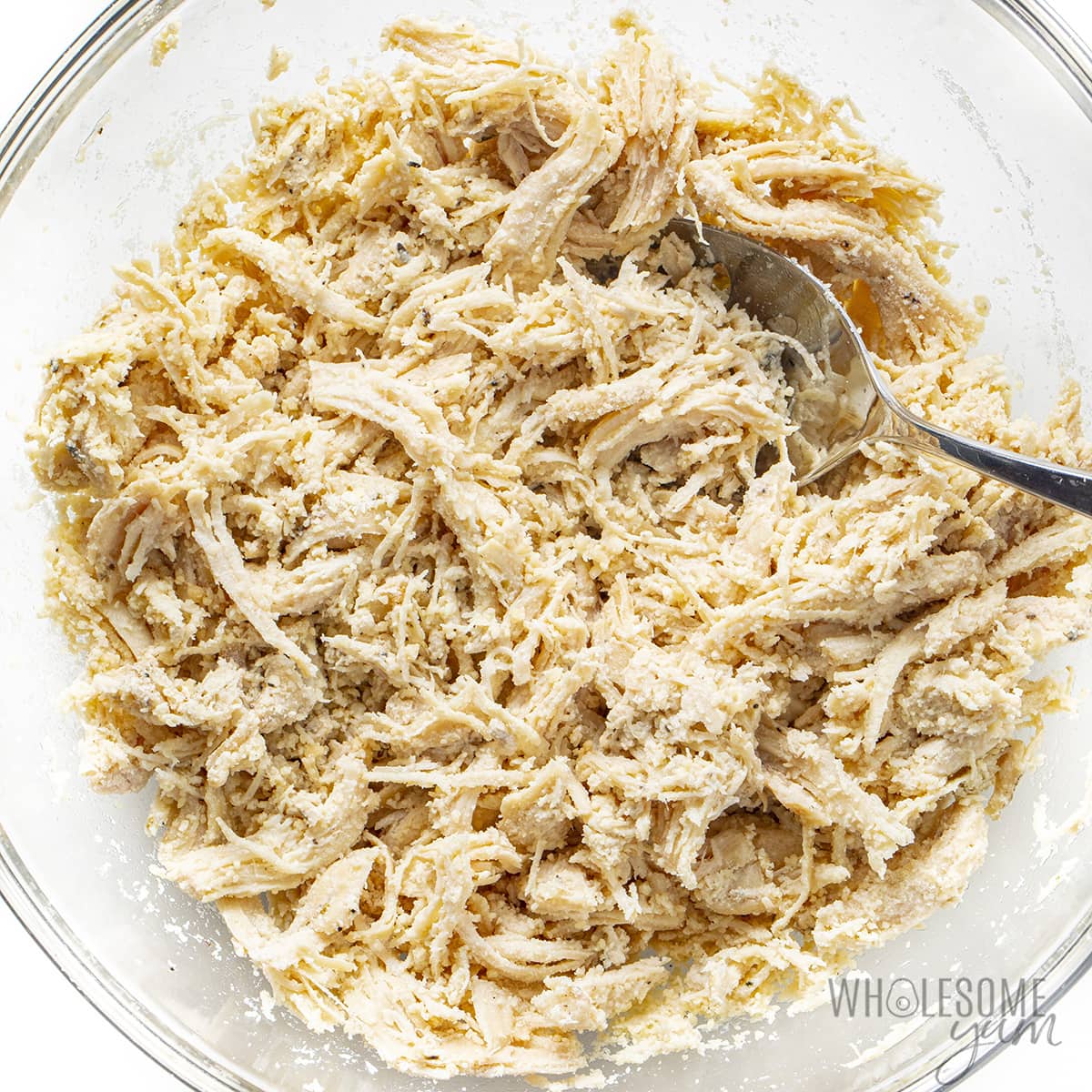 Shredded chicken, grated parmesan cheese, minced garlic, and sea salt in a bowl.