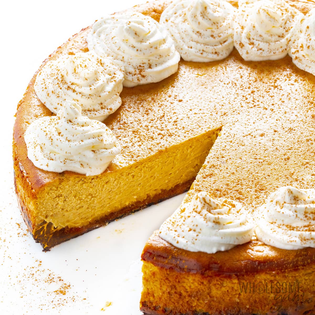 Whole low carb pumpkin cheesecake with slice removed.
