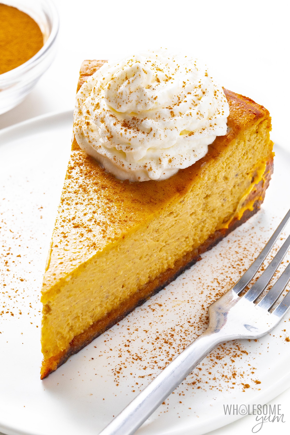 Place a slice of sugar-free pumpkin cheesecake on a plate with a fork.