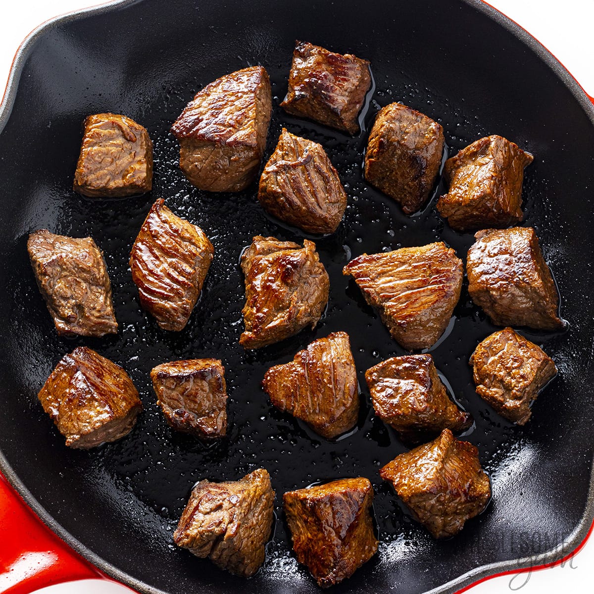 Seared sirloin steak tips in skillet.