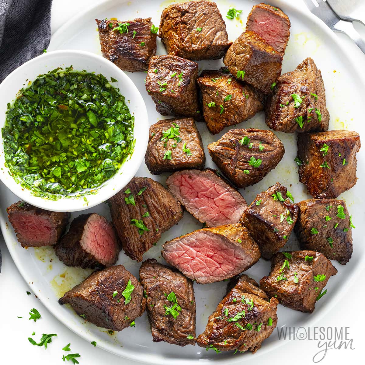 Sirloin steak tips with chimichurri sauce on a plate.