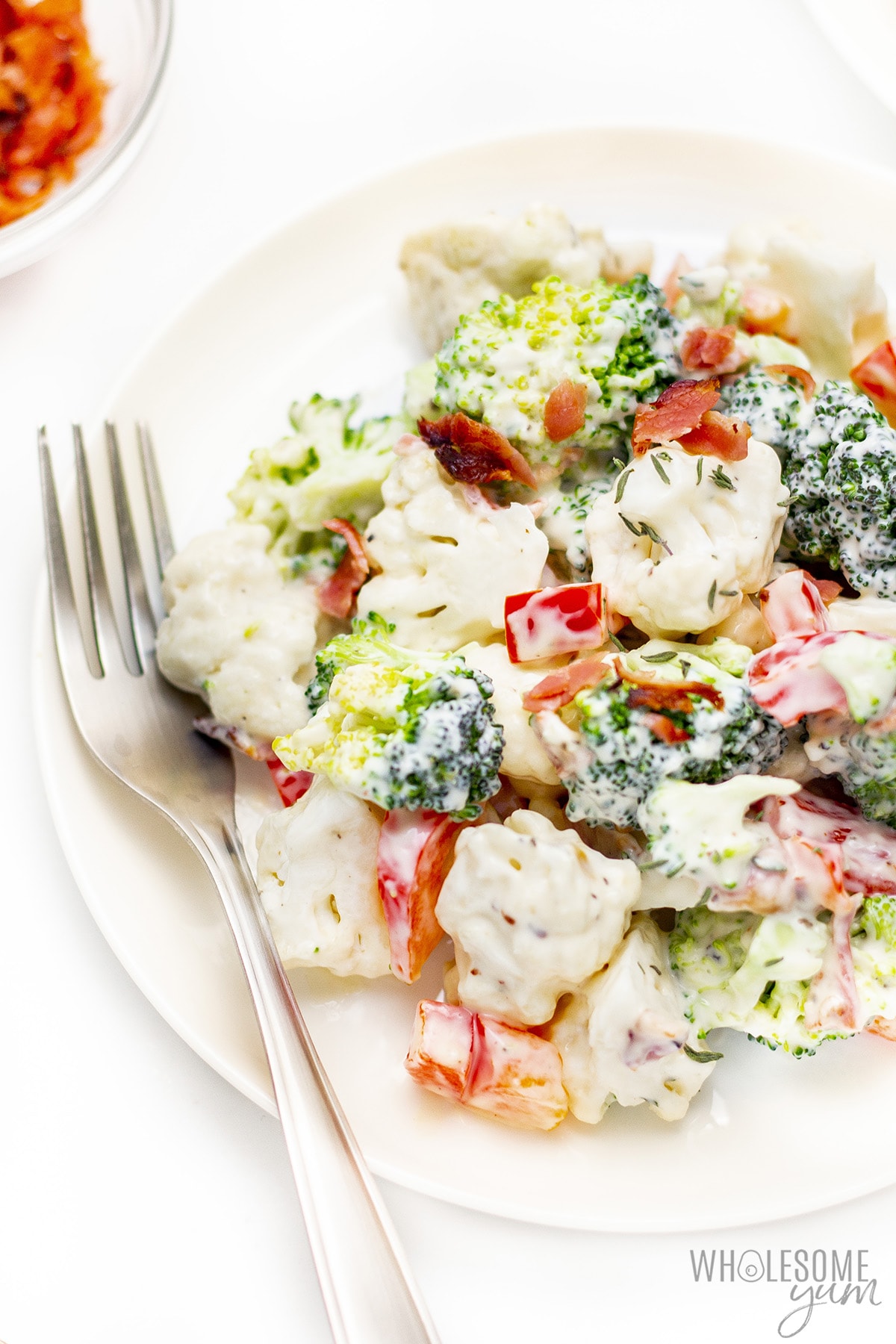 Broccoli cauliflower bacon salad on a plate with a fork.