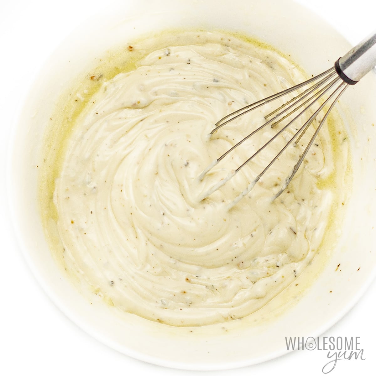 Dressing ingredients in a bowl with a whisk.