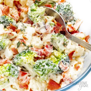 Broccoli cauliflower salad with bacon close up with a spoon.