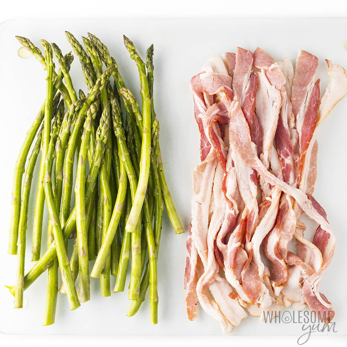 Trimmed asparagus next to slices of bacon.