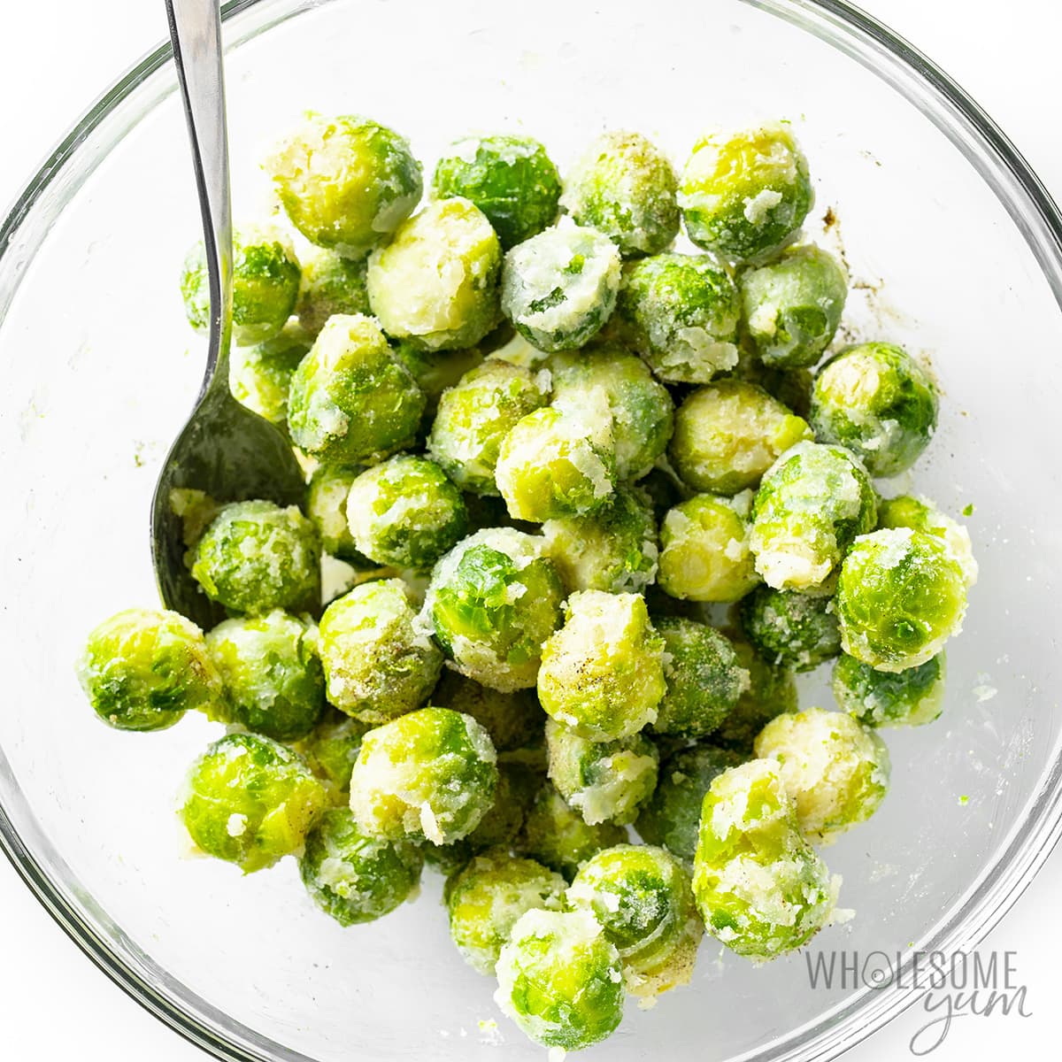 Brussels sprouts in a bowl tossed in seasonings.