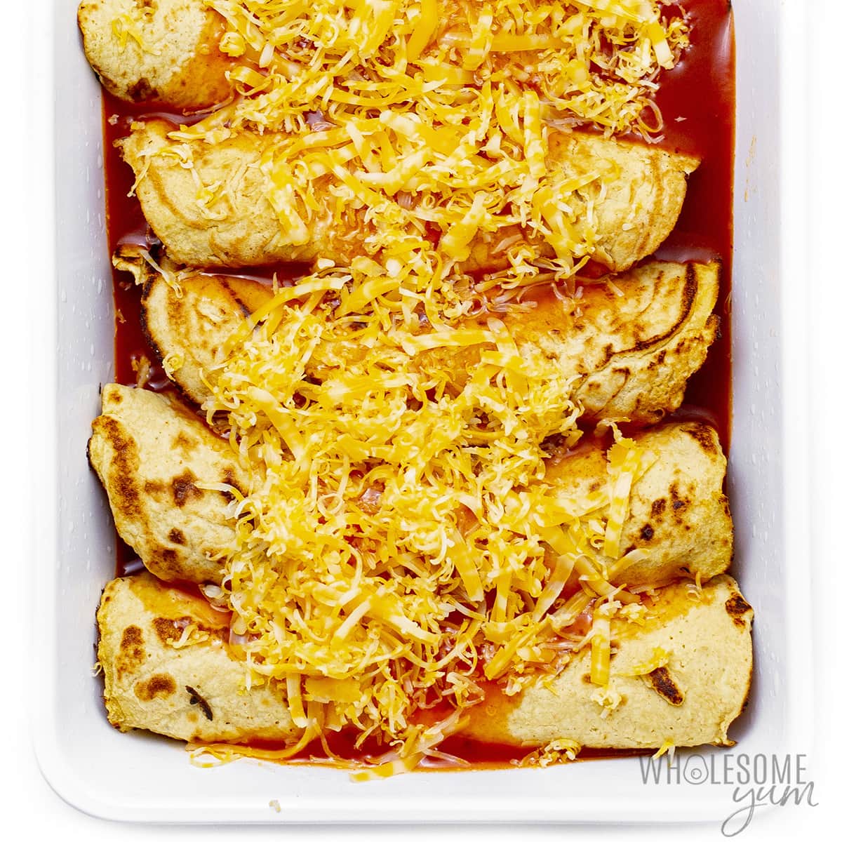 Keto enchiladas topped with shredded cheese.