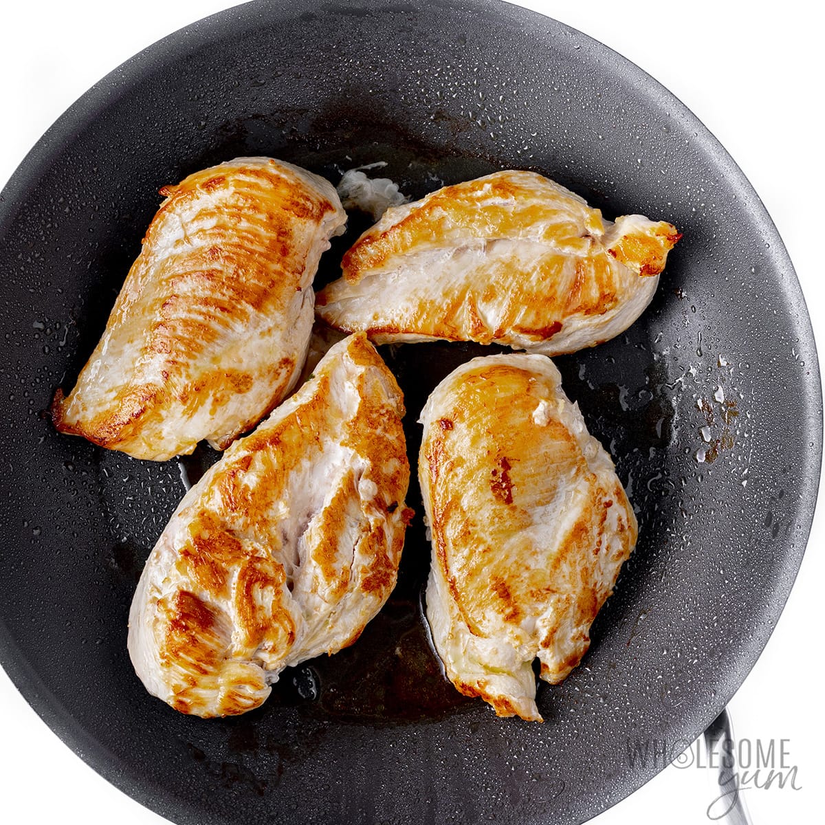 Chicken seared in a skillet.