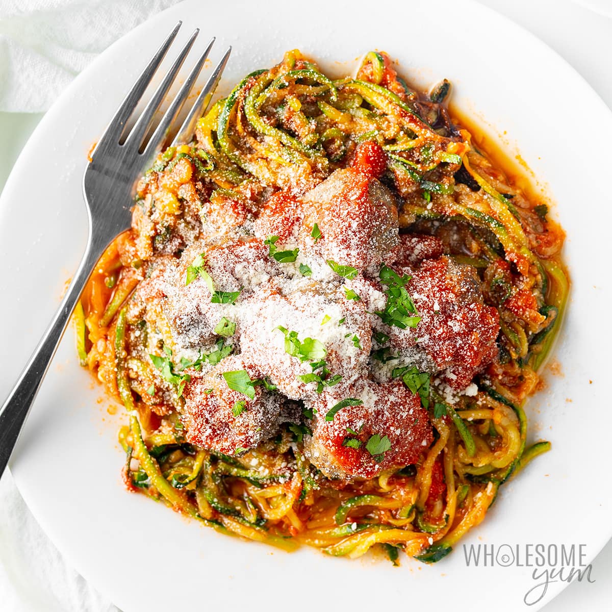 Zucchini spaghetti on a plate with grated parmesan.